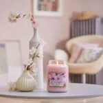 Brennende Cherry-Blossom-Kerze auf Tisch neben Blumenvasen