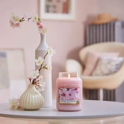 Brennende Cherry-Blossom-Kerze auf Tisch neben Blumenvasen