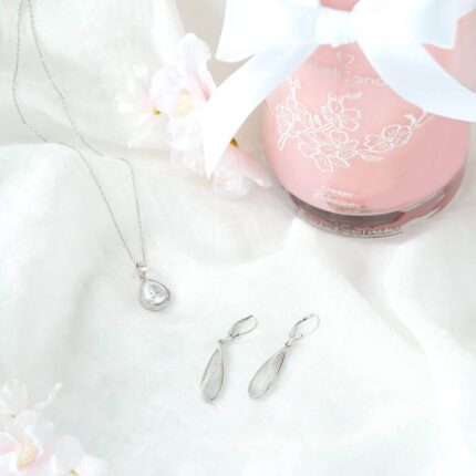 Halskette mit Anhänger und passende Ohrringe neben einer Cherry-Blossom-Kerze