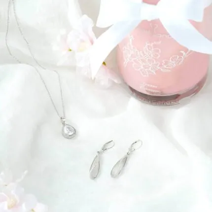 Halskette mit Anhänger und passende Ohrringe neben einer Cherry-Blossom-Kerze