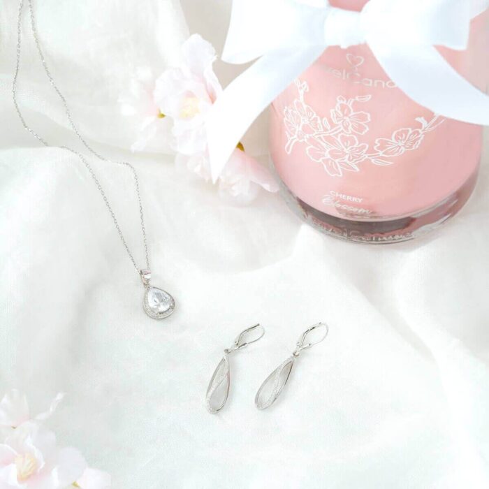 Halskette mit Anhänger und passende Ohrringe neben einer Cherry-Blossom-Kerze