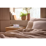 WoodWick Kerze Cherry Blossom & Vanilla auf einem Sideboard neben Geschenkbox