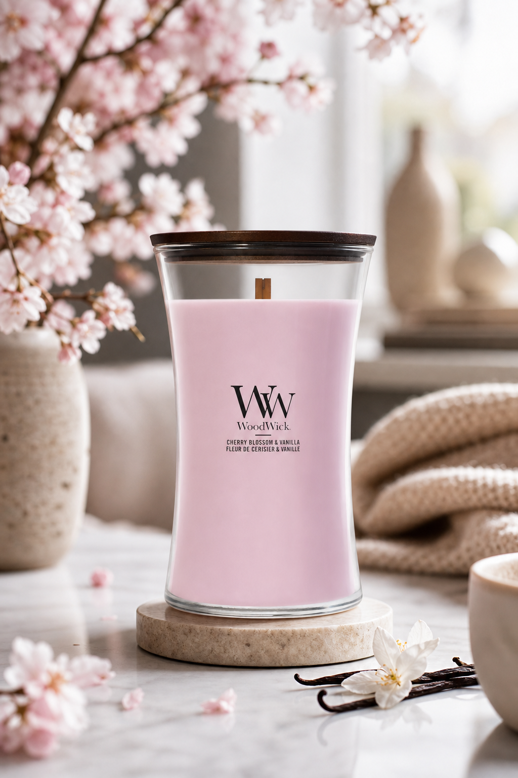 WoodWick-Kerze Cherry Blossom & Vanilla auf Untersetzer neben Kirschblüten