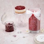 Cherry Kiss Kerze neben Schmuck, Kirschglas und Kirschkuchen