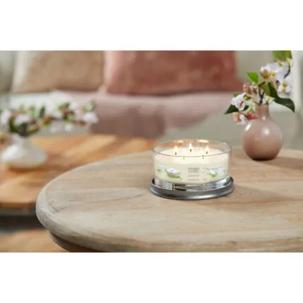 Brennende Clean Cotton Kerze im Glas auf einem runden Holztisch