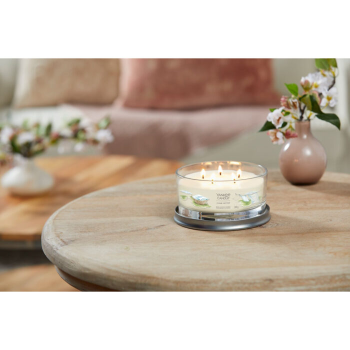 Brennende Clean Cotton Kerze im Glas auf einem runden Holztisch