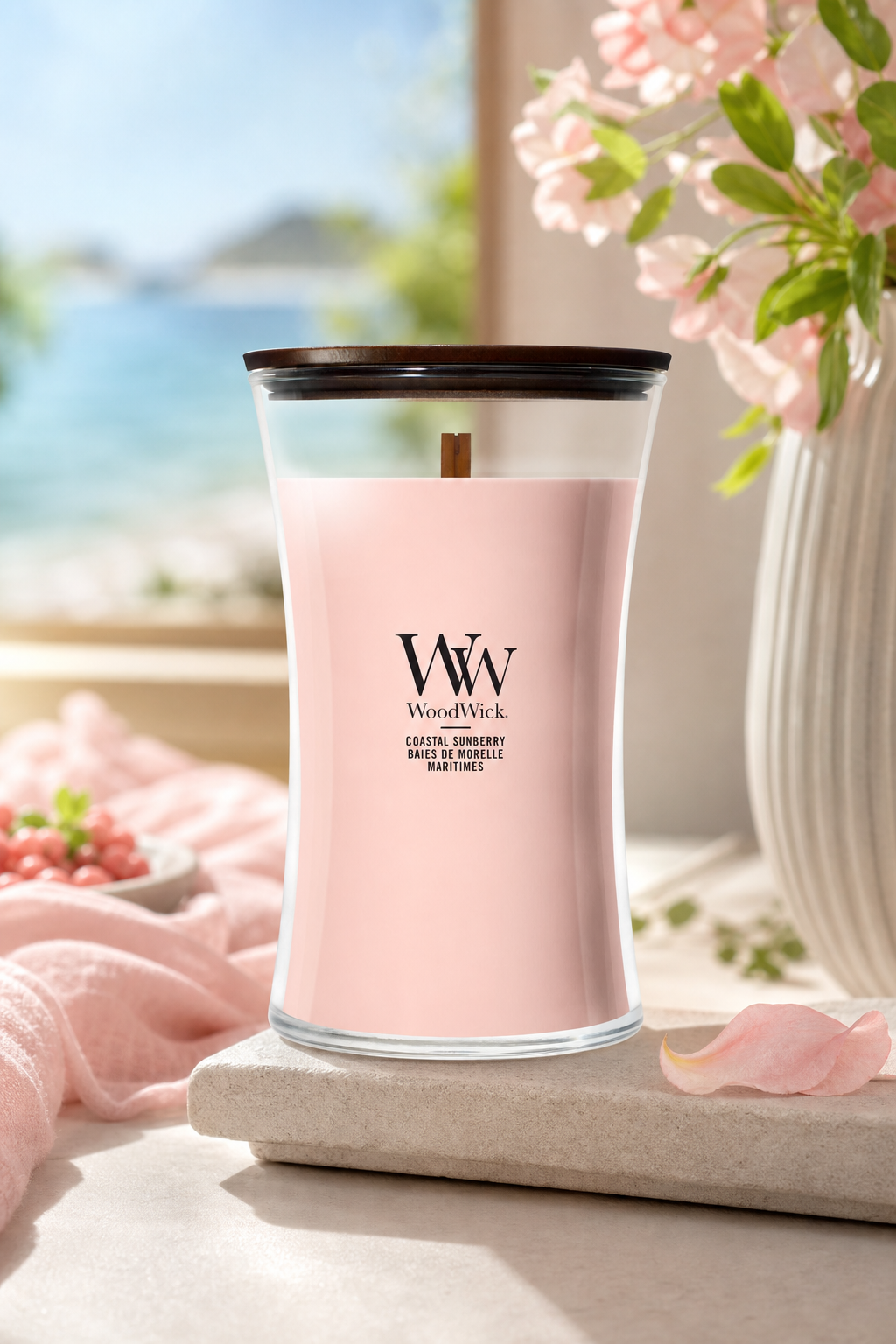 WoodWick Coastal Sunberry Kerze steht auf einer Ablage neben Blüten