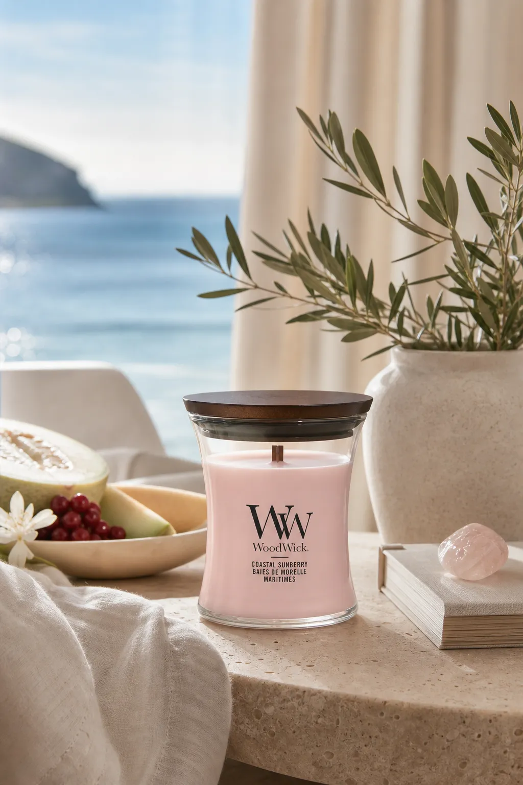 WoodWick Coastal Sunberry Kerze auf einem Tisch neben Büchern und Pflanze