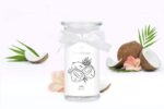 Coco-Bonito-Kerze zwischen aufgeschnittenen Kokosnüssen und Blüten