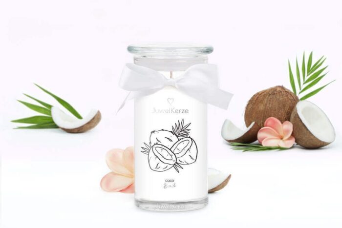 Coco-Bonito-Kerze zwischen aufgeschnittenen Kokosnüssen und Blüten