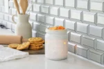Weiße Cookie Jar Duftlampe mit Wachsstücken neben Keksen und Küchenutensilien