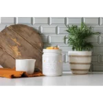 Weiße Cookie Jar Duftlampe mit Wachsstücken neben Pflanze und Keramikgefäß