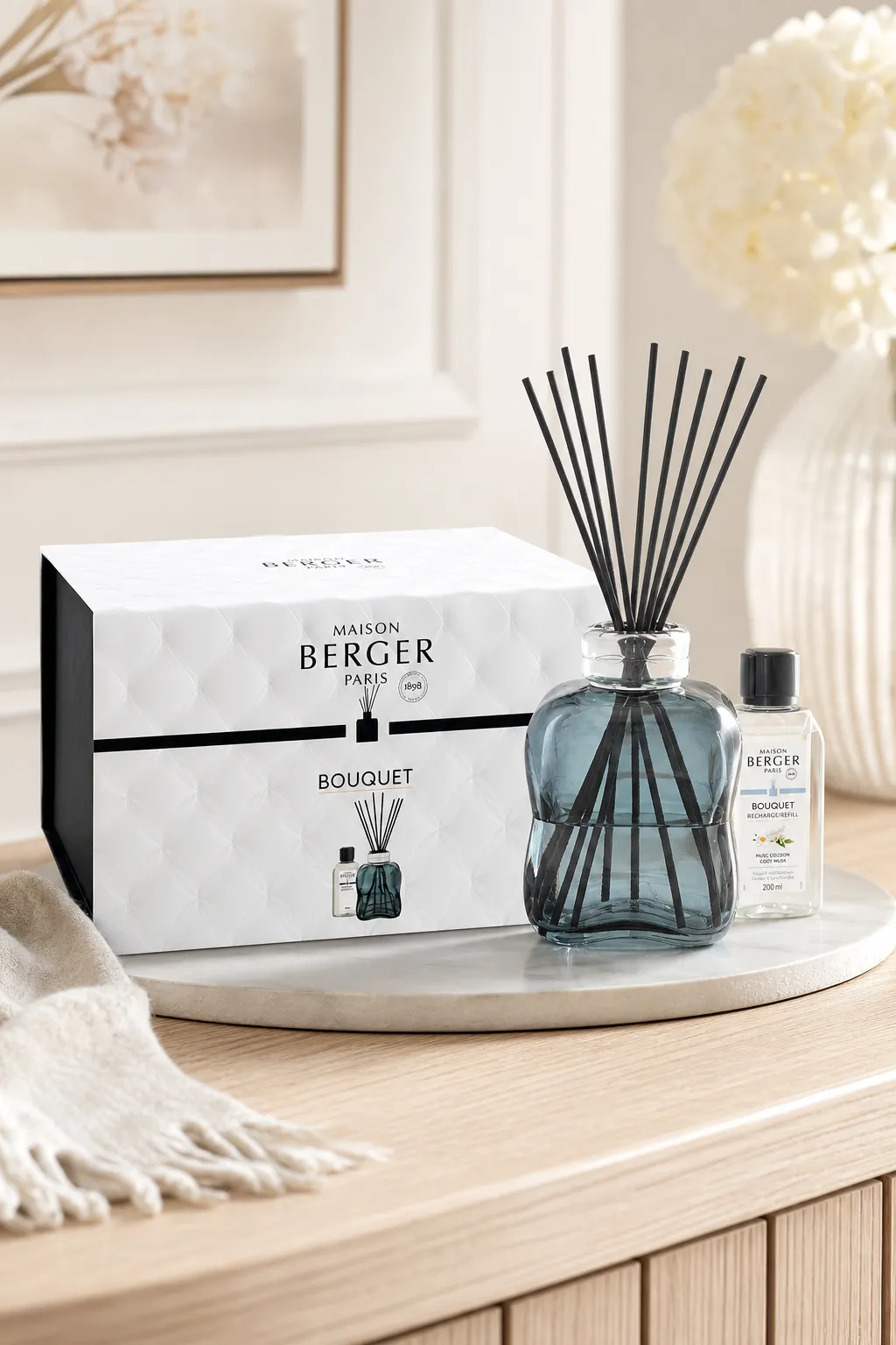 Diffuser-Set in Wohnumgebung Maison Berger Diffuser mit Duftstäbchen, Verpackung und Nachfüllflasche auf Tisch