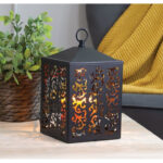 Schwarze Ornamentlaterne mit warmem Licht auf einem Tisch
