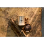 Brennende WoodWick Cypress Ore Kerze neben Holz und Schale mit getrockneten Pflanzen