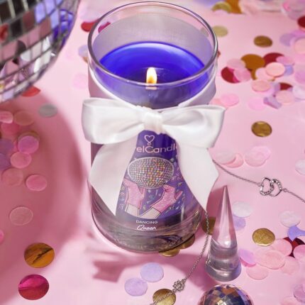 Brennende violette Kerze im Glas mit weißer Schleife und Armband daneben