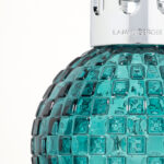 Detailansicht der türkisfarbenen Glasstruktur und silbernen Lampenkrone