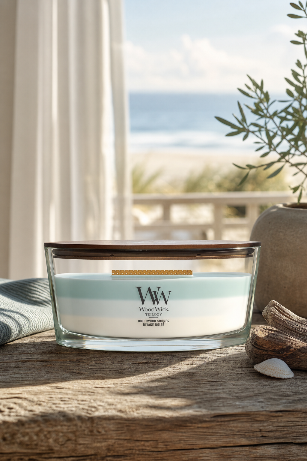 WoodWick Driftwood Shores Kerze auf einem Holztisch vor Meerblick