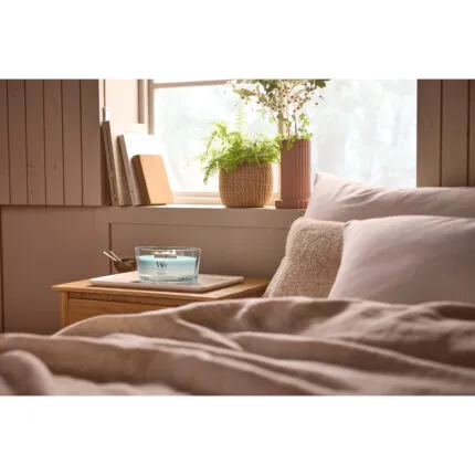 WoodWick Kerze auf einem Tablett neben einem Bett im Schlafzimmer