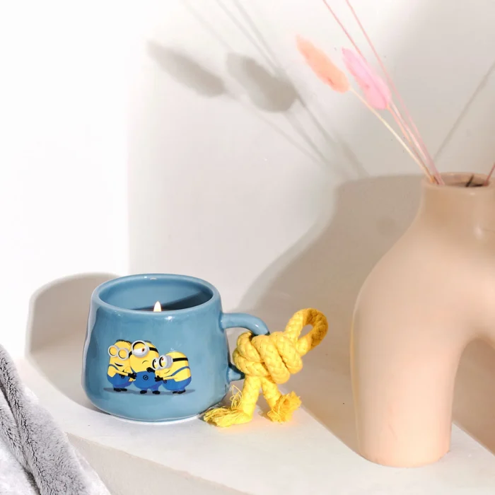 Blaue Minions-Tassenkerze mit brennender Flamme neben einer Vase