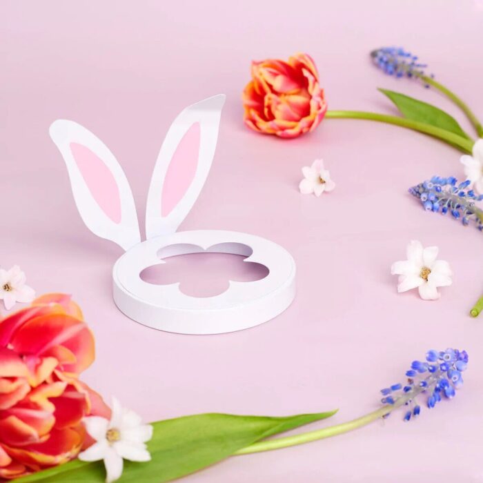 Weißer Lid mit Hasenohren und blütenförmiger Öffnung auf rosa Untergrund