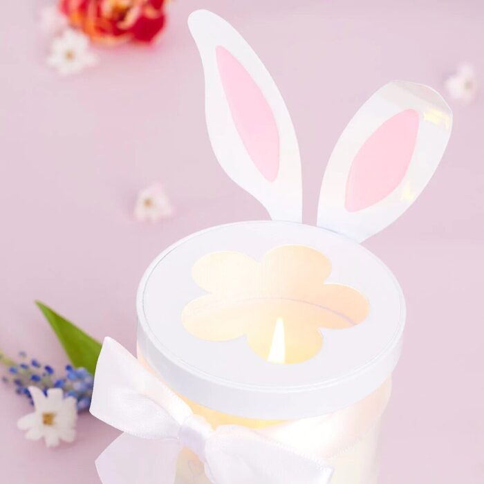 Easter Bunny Lid auf einer brennenden Kerze mit weißer Schleife