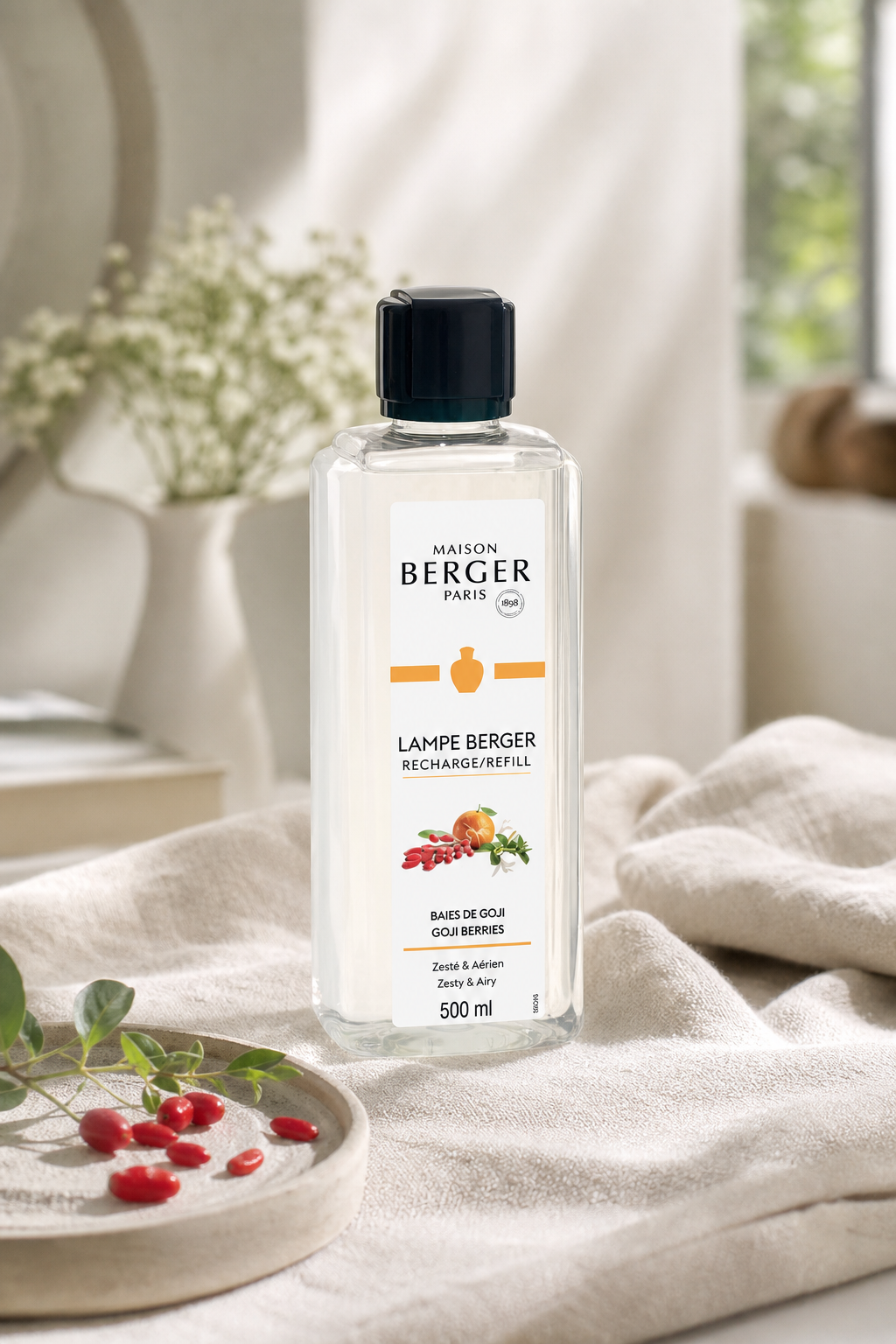 Maison Berger Goji-Beeren Nachfüllflasche liegt auf einem hellen Stoffbett neben Goji-Beeren