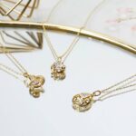 Person hält eine große Elegance Kerze neben einer goldenen Geschenkbox