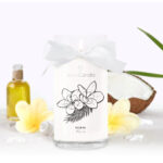 Weiße Jewel Candle Fleur de Monoi mit Schleife und brennender Flamme