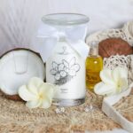 Fleur de Monoi Kerze neben aufgeklappter Kokosnussschale mit Halskette