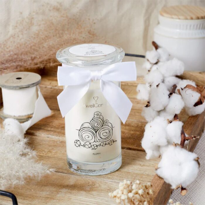 Fluffy Cotton Kerze mit Schleife auf Holztisch zwischen Baumwollzweigen