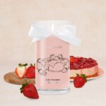 Rosa Kerze mit weißer Schleife und Erdbeer-Cheesecake-Illustration