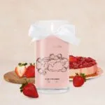 Rosa Kerze mit weißer Schleife und Erdbeer-Cheesecake-Illustration