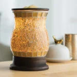 Beleuchtete Duftlampe mit goldfarbenem Glas auf einem Holztisch