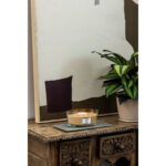 Brennende WoodWick Gilded Sands Kerze neben einer Zimmerpflanze