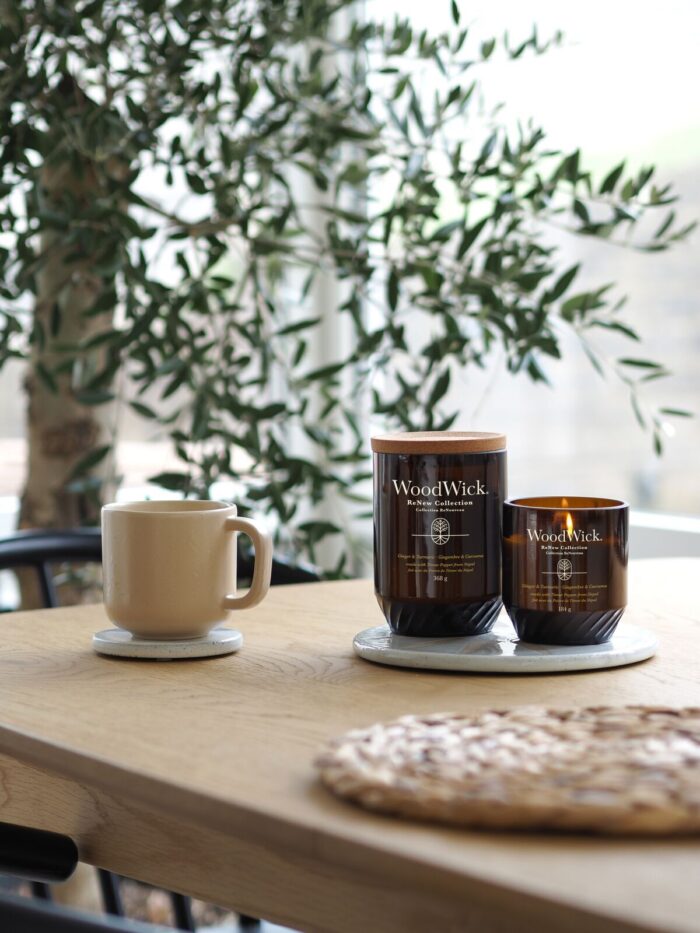 WoodWick Ginger & Turmeric Kerze brennt auf einem Beistelltisch