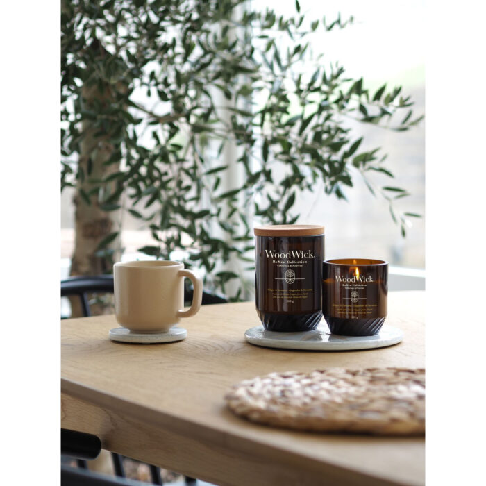 WoodWick Ginger & Turmeric Kerze mit Korkdeckel neben einer Tasse