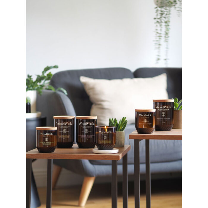 Brennende WoodWick Ginger & Turmeric Kerze neben Ingwer, Kurkuma und Pfeffer