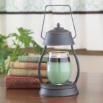 Laterne mit grünem Glasgefäß neben Büchern und Zimmerpflanze