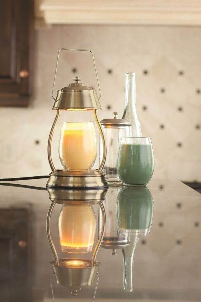 Leuchtende Laterne mit heller Kerze neben Glas und Metallbehälter