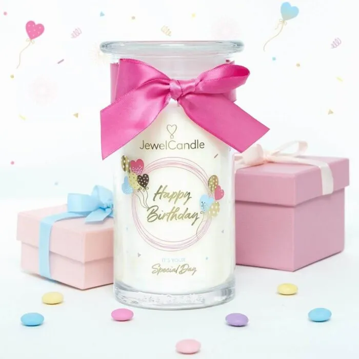 Happy-Birthday-Kerze mit Schleife neben mehreren hängenden Schmuckanhängern