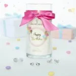Happy-Birthday-Kerze mit pinker Schleife zwischen zwei Geschenkboxen