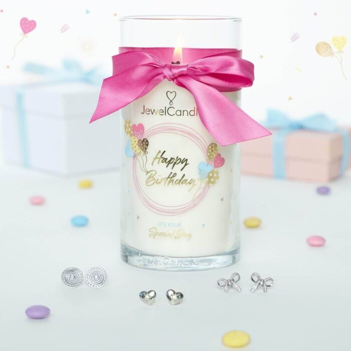 Happy-Birthday-Kerze mit rosa Schleife zwischen zwei Geschenkboxen