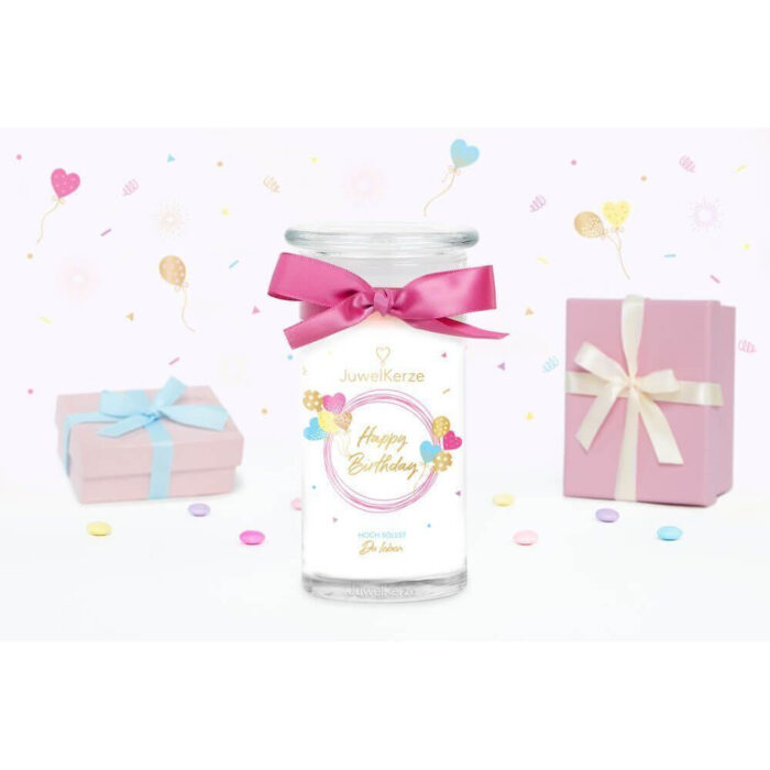 Happy-Birthday-Kerze mit Schleife zwischen rosa Geschenkboxen und Konfetti