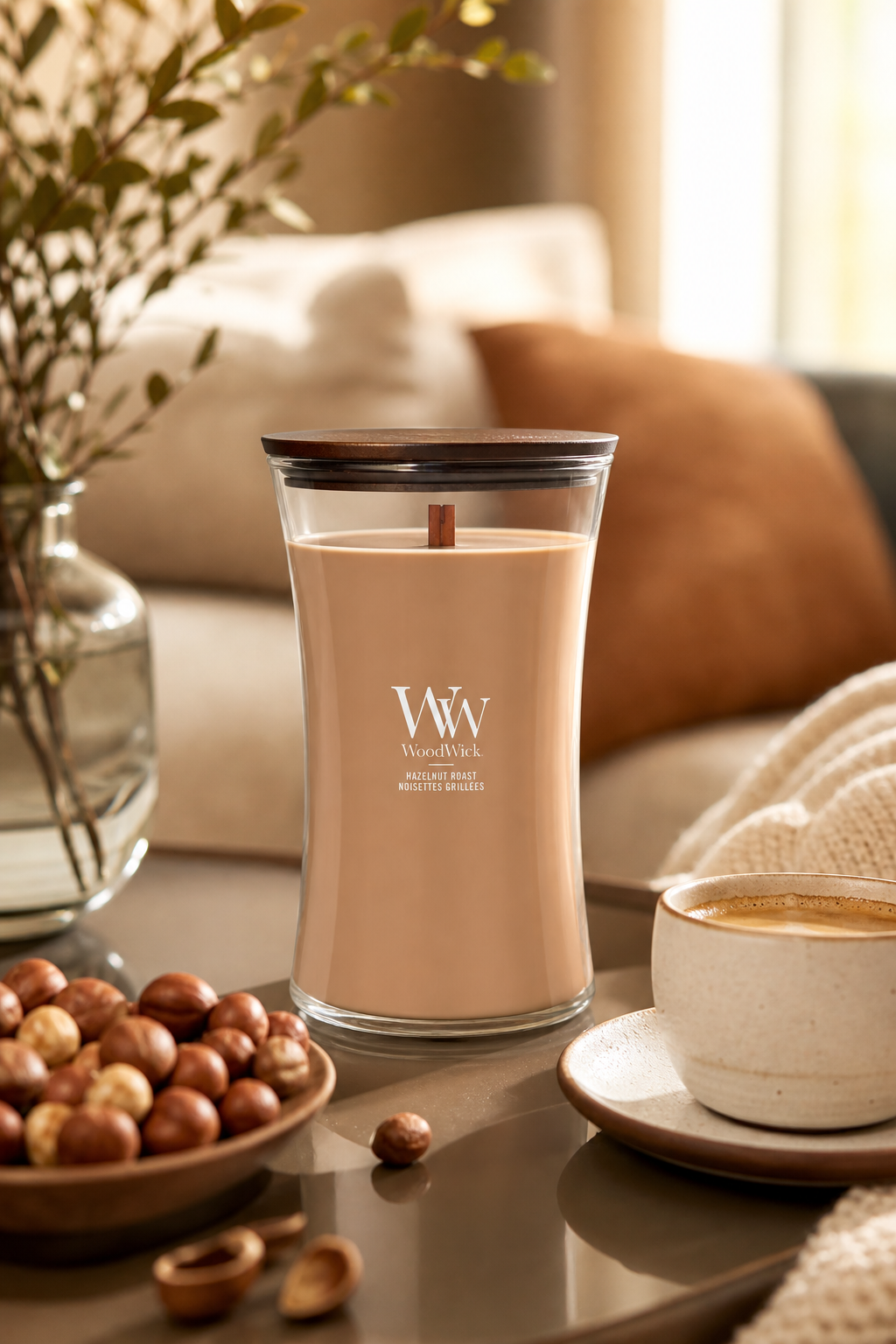WoodWick Hazelnut Roast Kerze neben Haselnüssen und Tasse im Wohnambiente