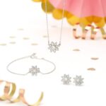 Halskette, Armband und Blumenohrringe neben der Congratulations-Kerze