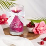 Brennende Hibiscus-Juicy-Raspberry-Kerze mit sichtbarer Halskette und weißer Schleife