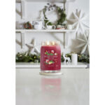 Brennende Yankee Candle Holiday Cheer Kerze auf Untersetzer am gedeckten Tisch