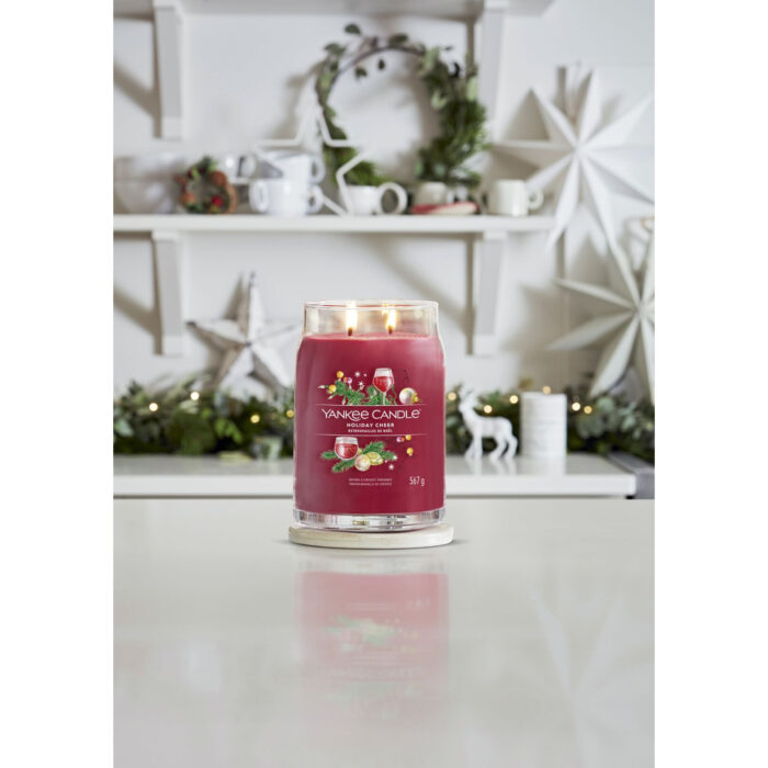Brennende Yankee Candle Holiday Cheer Kerze auf Untersetzer am gedeckten Tisch