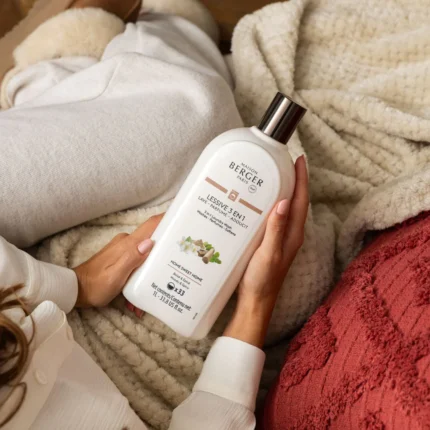 Maison Berger Paris Wäsche-Elixier wird vor gefalteter Wäsche gehalten